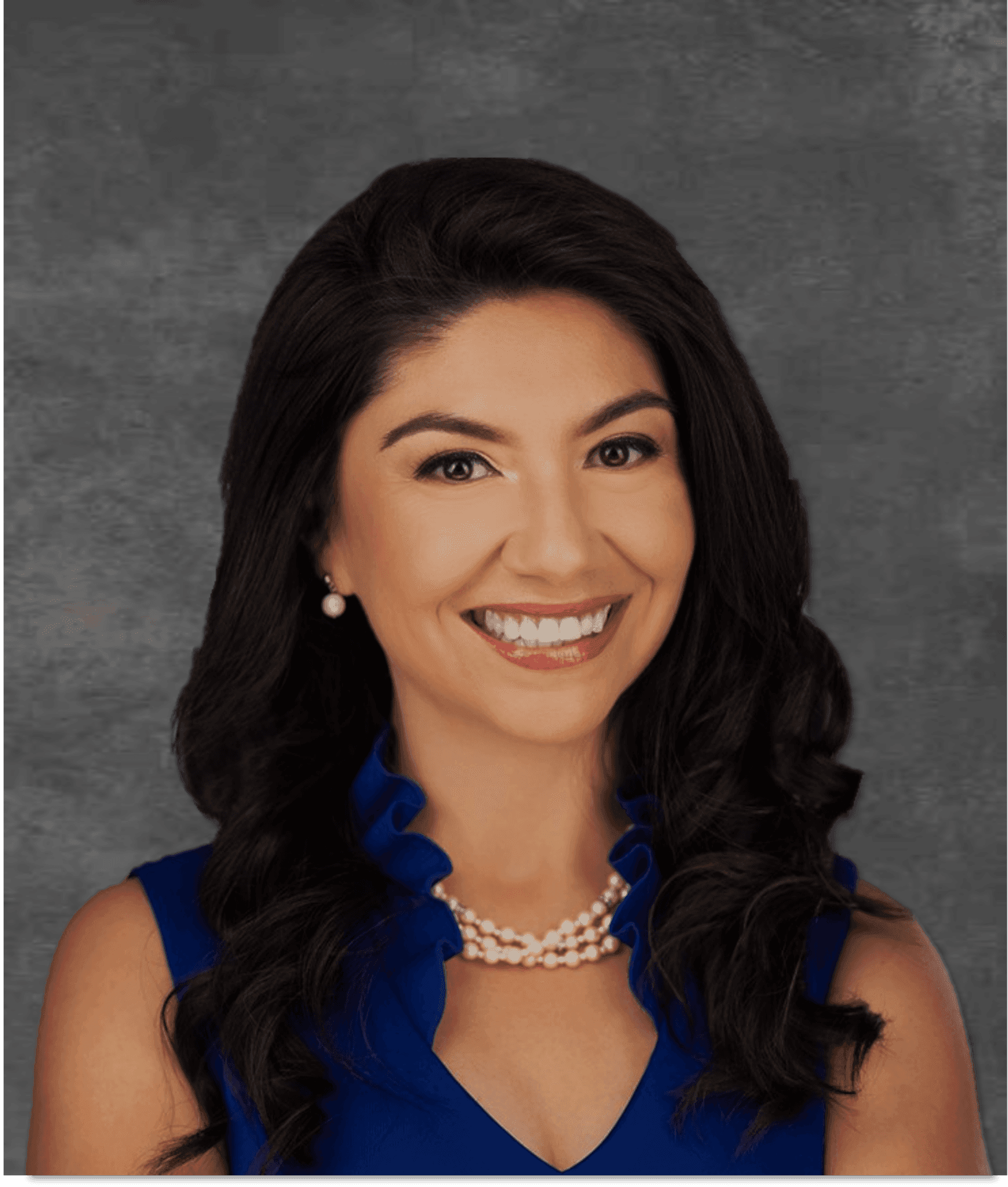 Smiling woman with dark hair in blue dress and pearl necklace against a gray background.