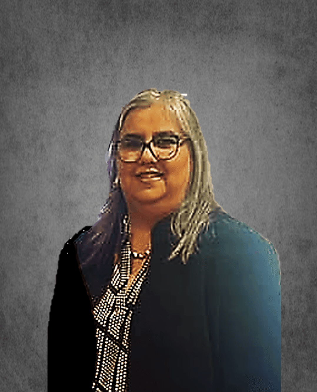 Person wearing glasses and a patterned shirt under a black blazer, with gray background.