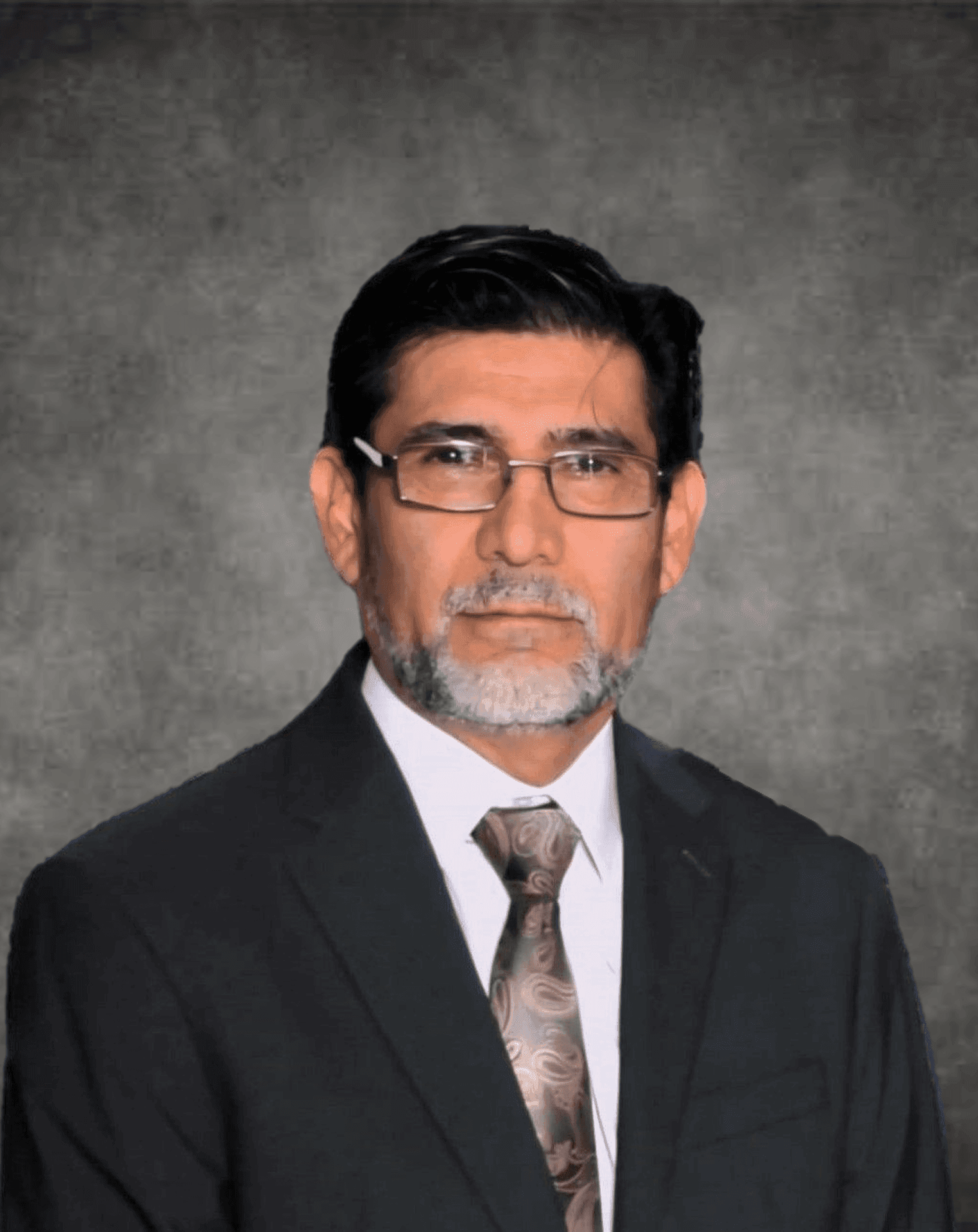 Man with glasses and beard in formal suit against dark textured background.