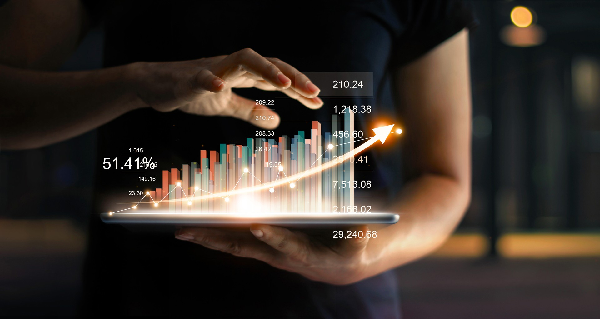 Empresario sosteniendo tablet y muestra un holograma virtual creciente de estadísticas, gráfico y tabla con flechas sobre fondo oscuro. Mercado de valores. Concepto de crecimiento, planeación y estrategia de negocio.